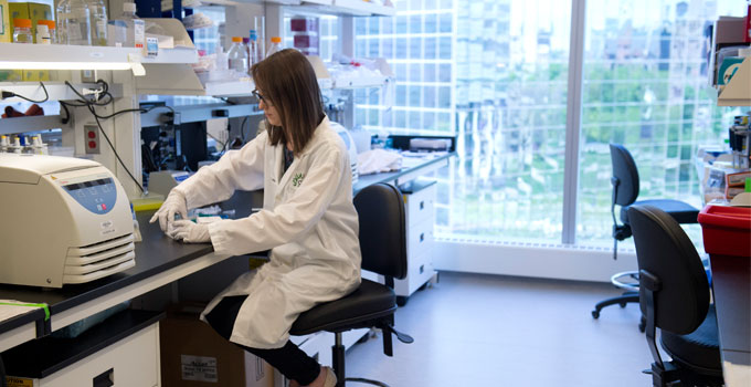 A lab technician works at a bench