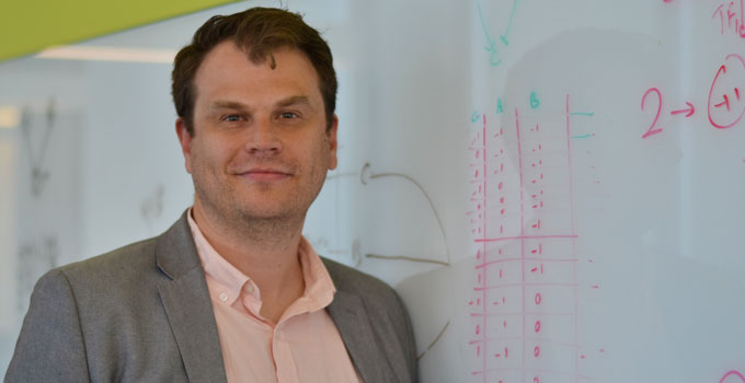 Dr. Michael Fraser poses for a photo in front of a whiteboard